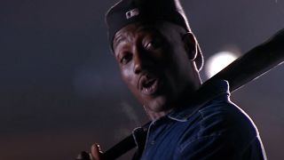 Wesley Snipes holding a bat and wearing a ball cap backwards