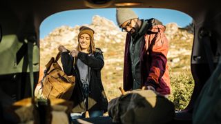 Couple unpacking camping gear from car