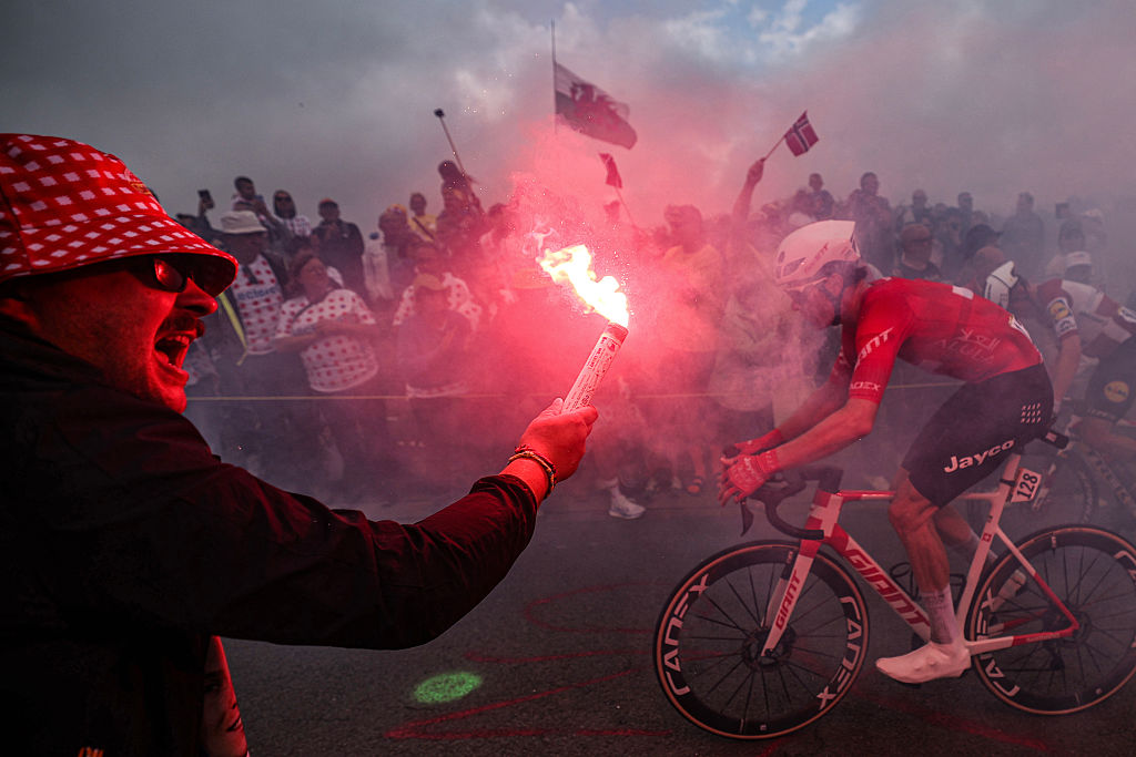 A spectator waves a flare as Team Jayco AlUla team&#039;s Swiss rider Mauro Schmid cycles in an ascent in the final kilometres of the 2nd stage of the 112th edition of the Tour de France cycling race, 209.1 km between Lauwin-Planque and Boulogne-sur-Mer, Northern France, on July 6, 2025. (Photo by Anne-Christine POUJOULAT / AFP) (Photo by ANNE-CHRISTINE POUJOULAT/AFP via Getty Images)
