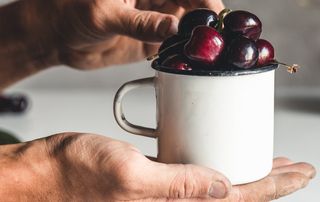 A tin cup full of cherries