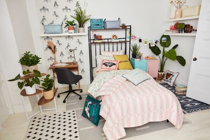 The Novogratz Waverly pink tile Comforter Set in a dorm room with lots of throw pillows, a deskand removable wallpaper