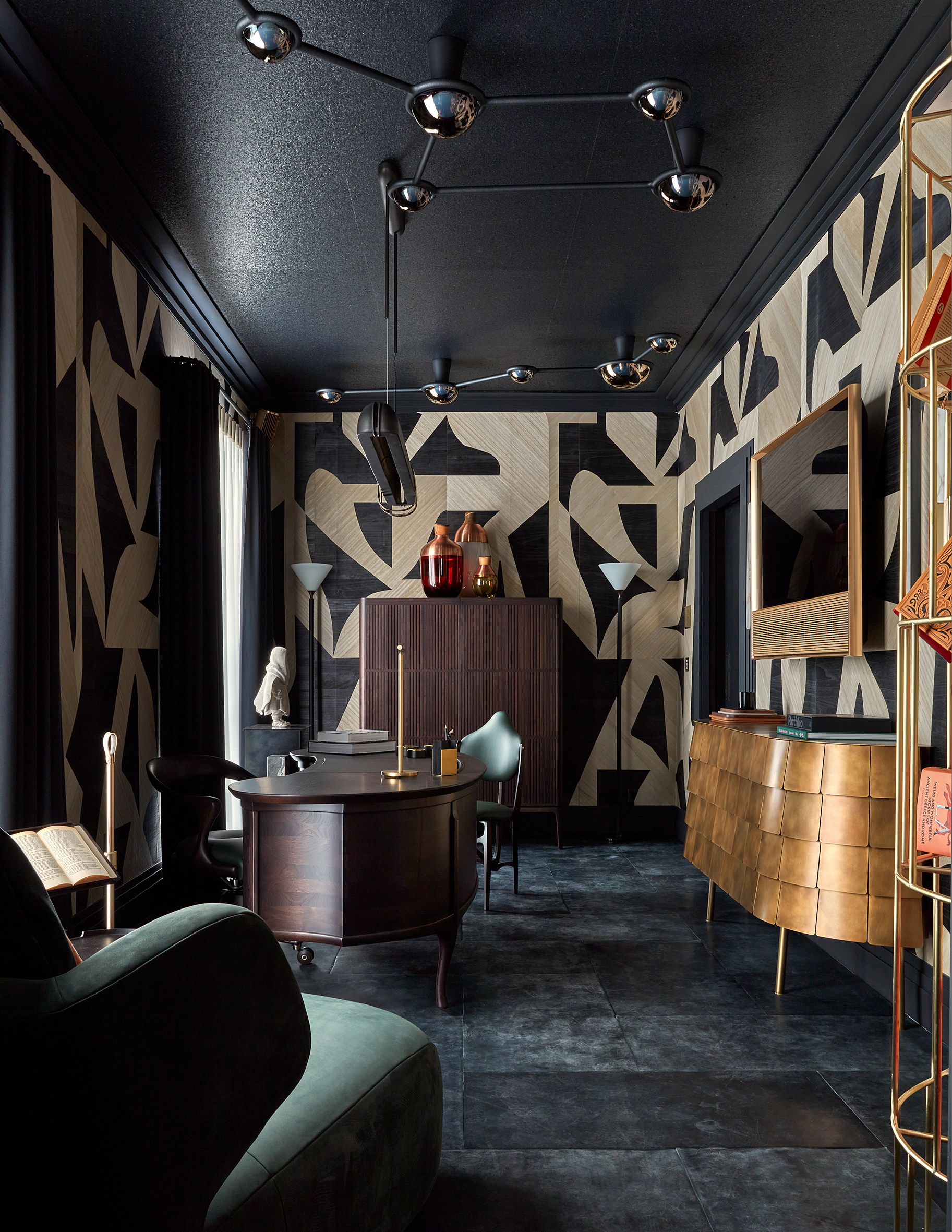 a home office with black and white wallpaper, a black ceiling, black floor and modern wood and brass furniture
