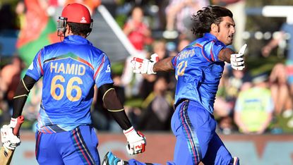Afghanistan batsman Shapoor Zadran celebrates with teammate Hamid Hassan after hitting the winning runs to defeat Sco