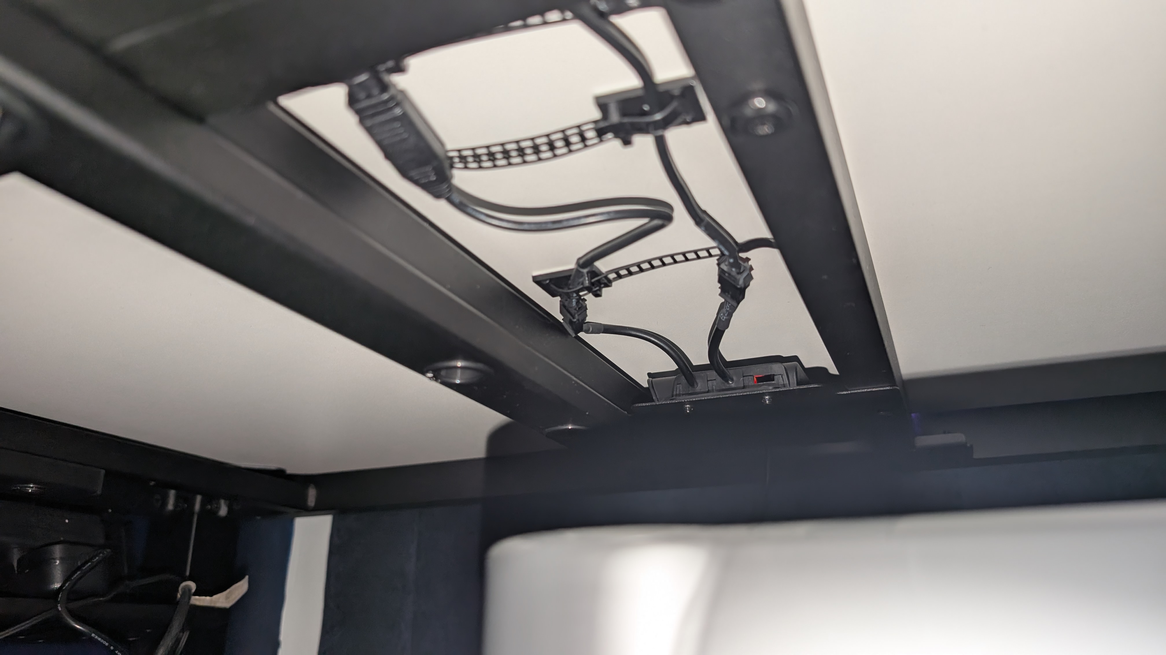 Closeup of the ARGB lighting controller and cabling on the underside of the Eureka Ergonomic GTG Wave gaming desk.