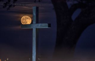 The full Thunder Moon appears to perch atop a wooden cross in this photo taken from the Belin Memorial United Methodist Church in Murrells Inlet, South Carolina, on Sunday (July 9) at 9:06 p.m. EST (0106 GMT on July 10).