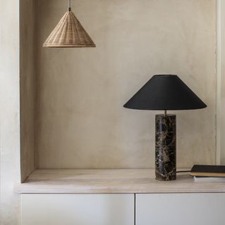 Living room shelf with beige lime wash wall and black lamp.
