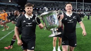 Two New Zealand players carry the Bledisloe Cup.