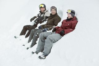 Three men sitting in snowbank