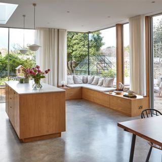 an open plan kitchen diner with cover window seating, and ceiling hung voile curtains