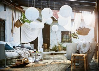 Outdoor pendant lights from Ikea decorating a bright outdoor space, with plenty of furniture, and white brick walls in the background
