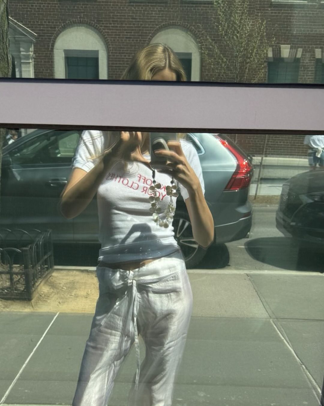 Courtney Grow wearing white silky drawstring pants and a graphic white T-shirt.