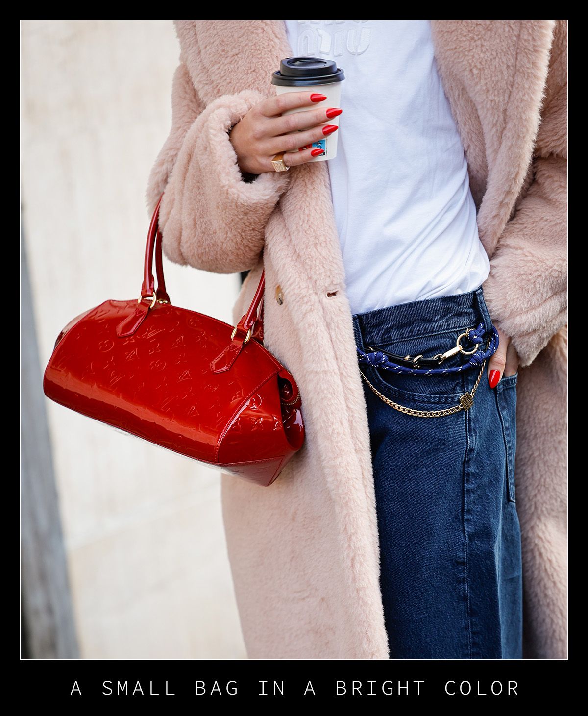 Woman in a coat, jeans, and red bag.