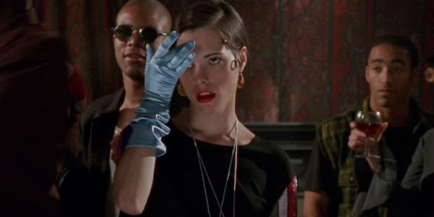 parker posey as mary wearing a blue glove and holding her hand to her head at a party in the movie party girl