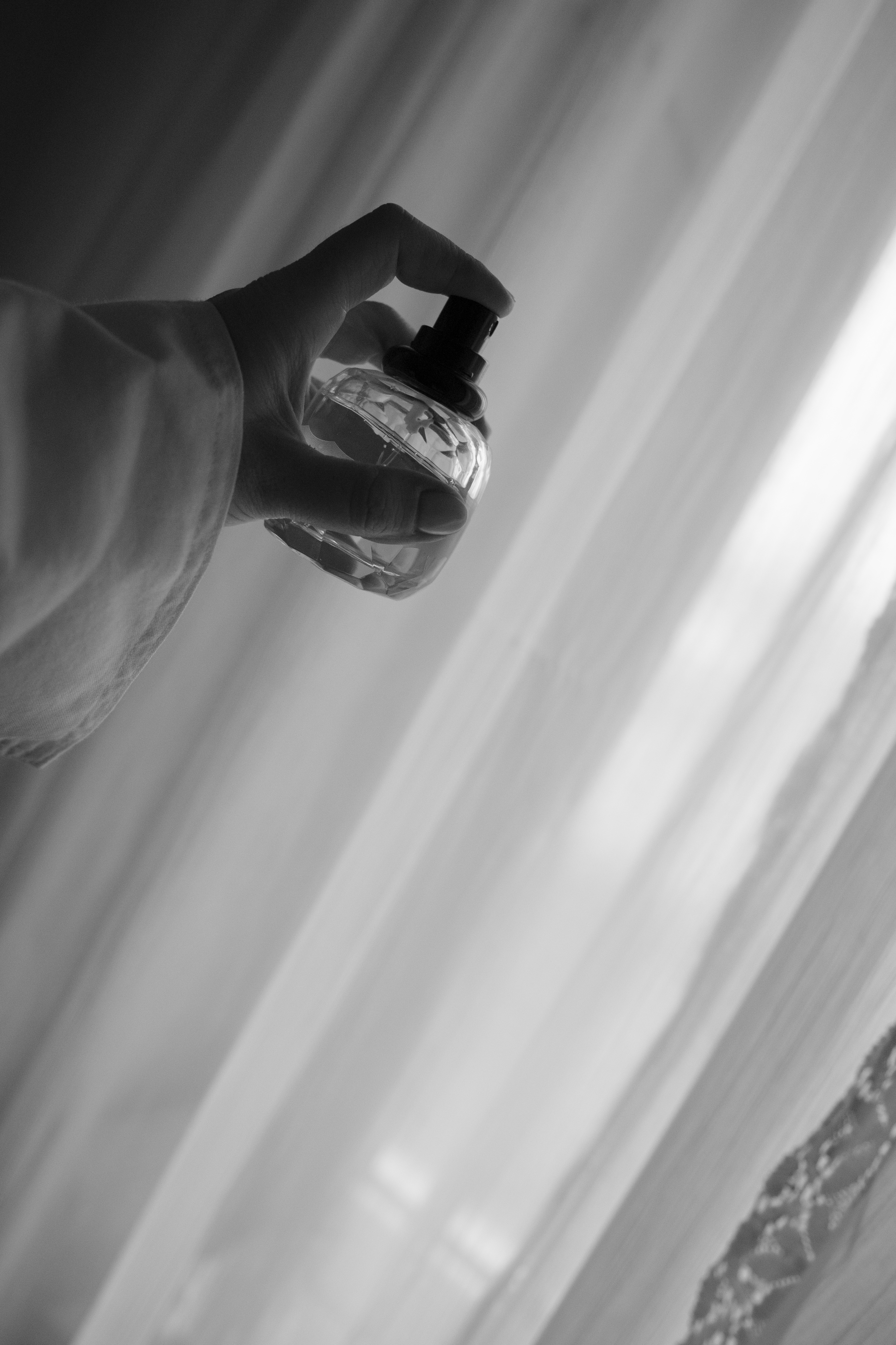 Someone holding and presumably about to spray a bottle of perfume