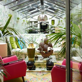 conservatory with leaf-print wallpaper and oversized mirror