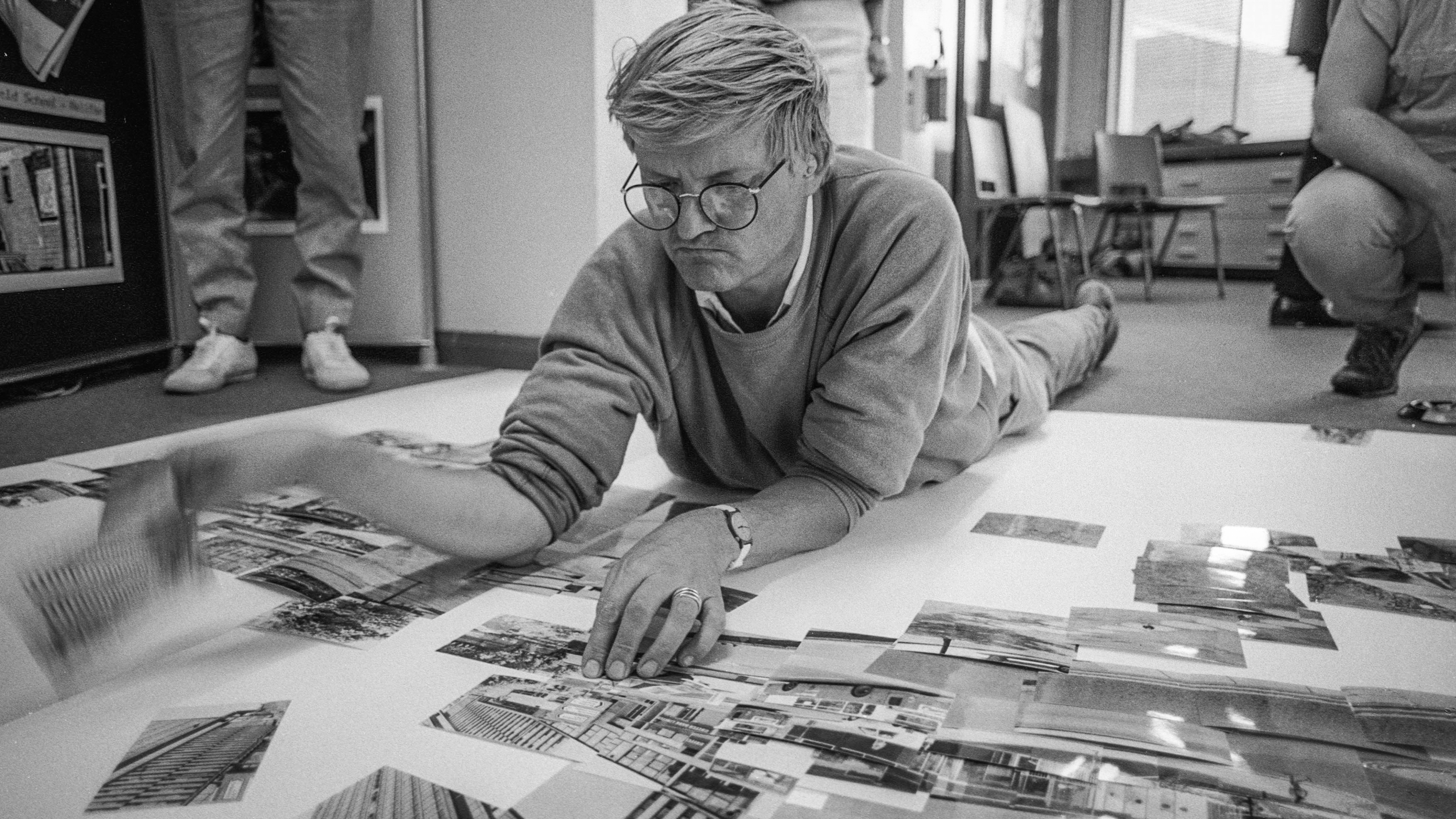 David Hockney lying on the floor, surrounded by polaroids