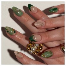 a close up of a manicure with green nail polish and gold and pearl accents