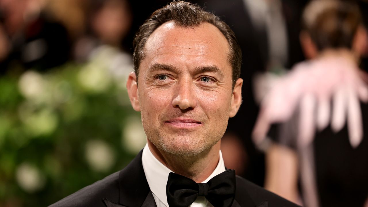 Jude Law wears a bow tie and smiles on the red carpet