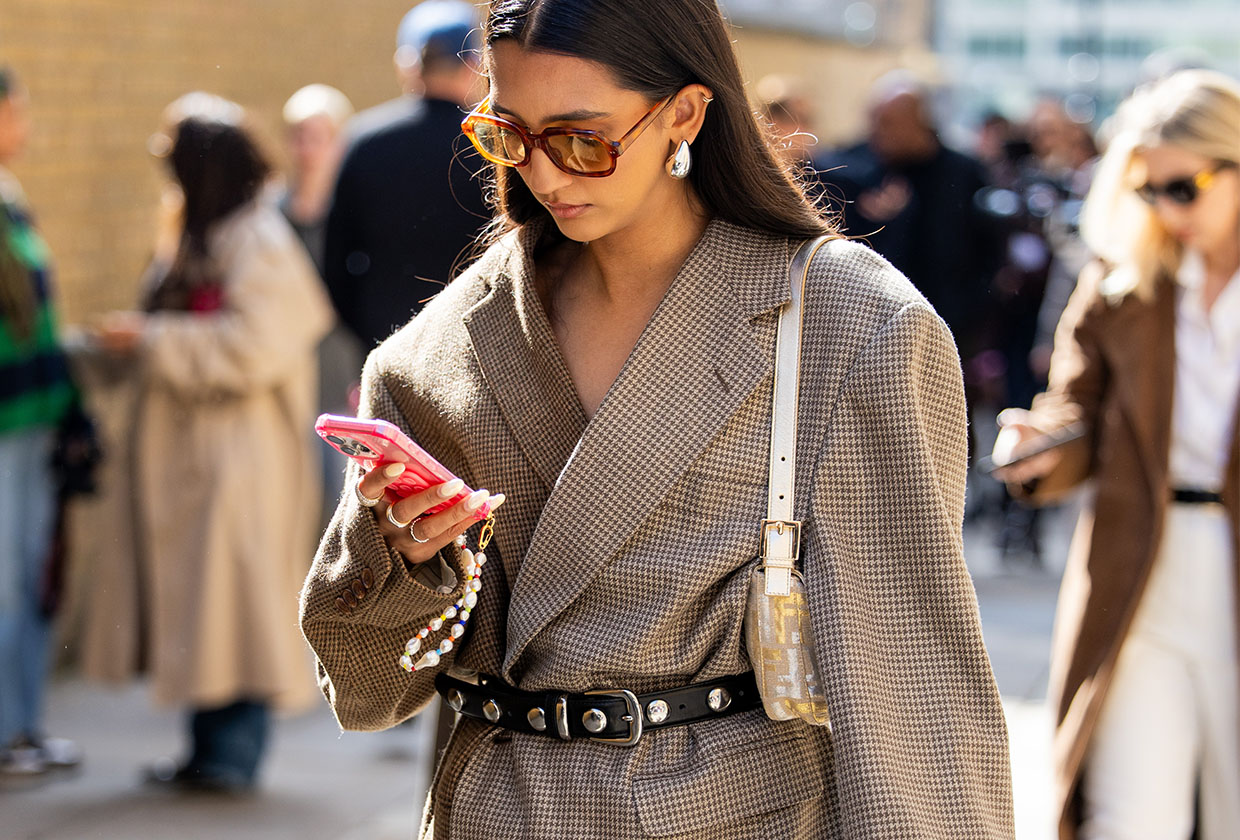 Woman in blazer looking at her phone.