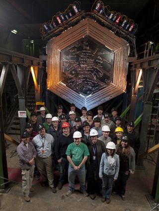 Scientists stand with the Minerva neutrino detector, located 330 feet underground at Fermi National Accelerator Laboratory