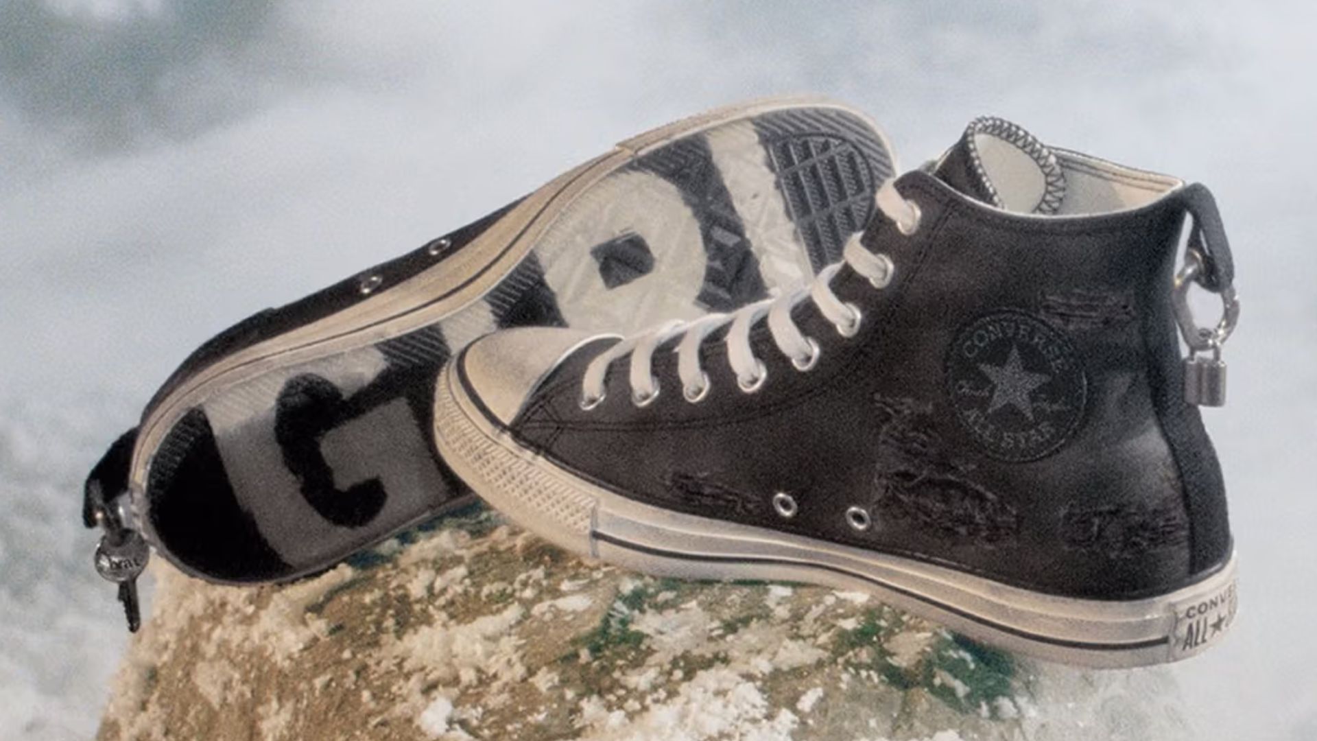 an image of the Charli XCX x Converse in black. One shoe is on its side showing the sole which has 'party' written across one and 'girl' across the other.