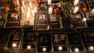 Candles and flowers placed near photos of journalists killed during fighting between Israel and Hamas