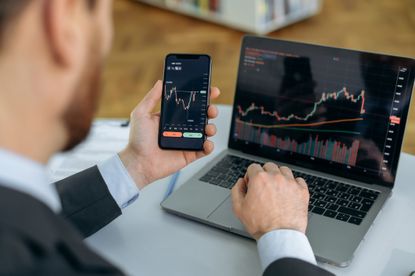 Crypto trader investor broker using cellphone and laptop for cryptocurrency financial market analysis