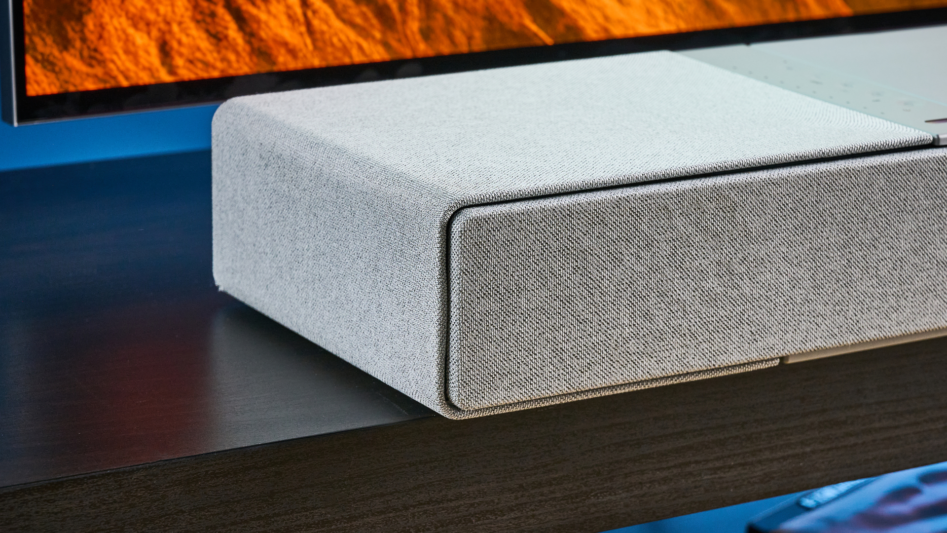 the KEF XIO soundbar in gray photographed with a TV and the Tom's Guide blue background