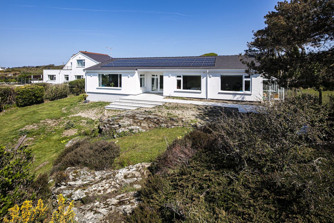 exterior of white rendered bungalow on sloping slot
