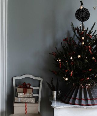 Christmas tree on mantel with chair and piled up presents alongside