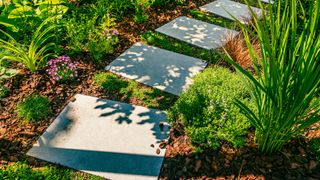 Curved garden path with slabs laid between bark mulch