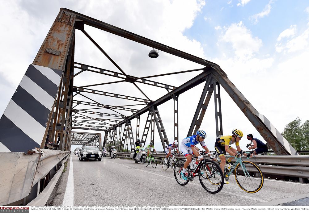 The peloton crosses a bridge in the Italian countryside.