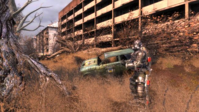 Stalker: Shadow of Chernobyl - A character in metal armor stands beside a broken car outside an abandoned parking garage