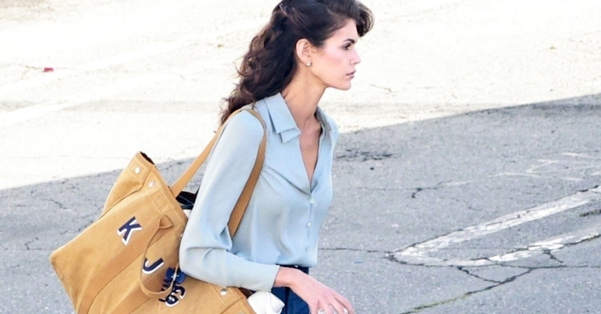First look at Kaia Gerber in Ryan Murphy's new 80s thriller, "The Shards." Kaia showed off an uncanny resemblance to her mom, Cindy Crawford, with a classic 80s hairstyle and wardrobe. She's wearing a silk blue blouse, bootcut jeans, and Ugg Classic Micro mules.