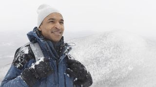 A hiker wearing a beanie in the snow