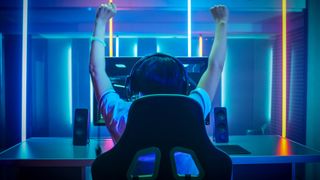 Back of person gaming on a PC, hands in the air in triumph