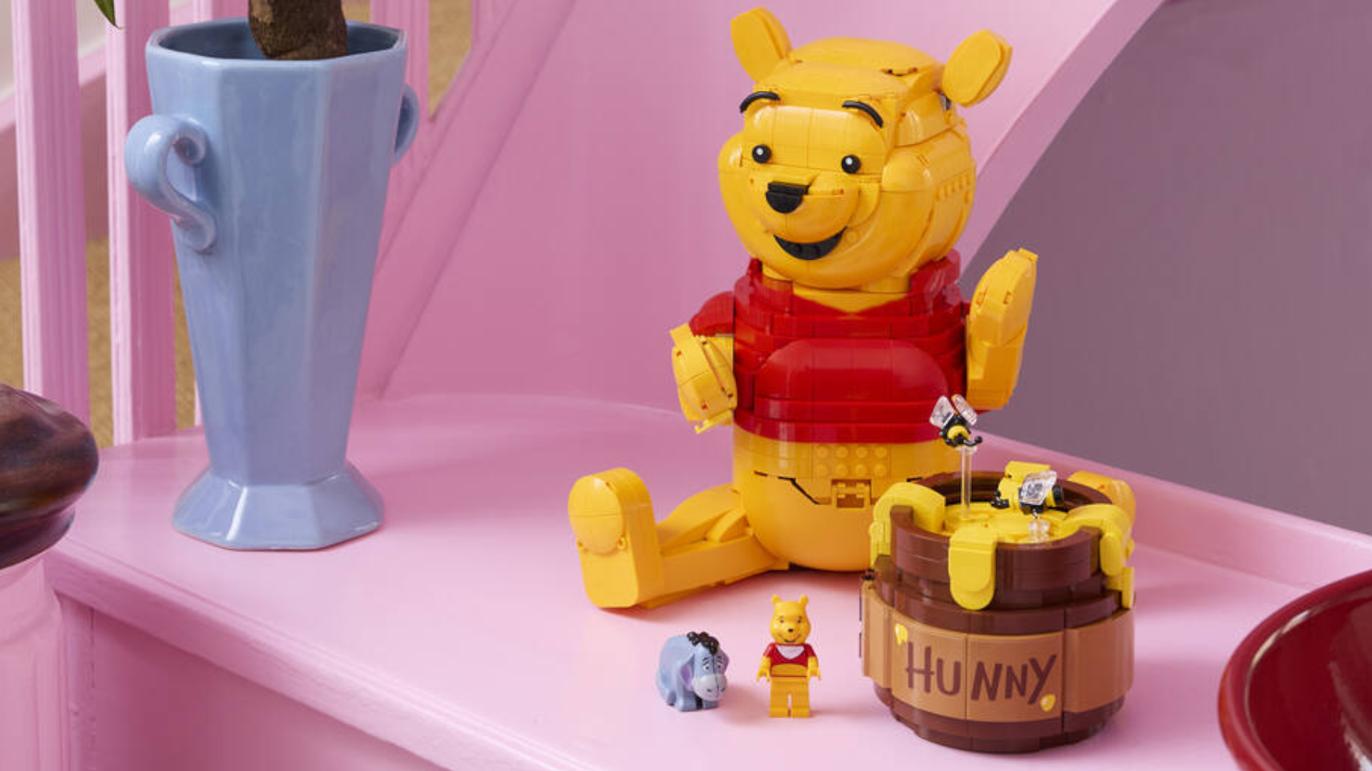 Lego Winnie the Pooh on a pink table, beside a vase