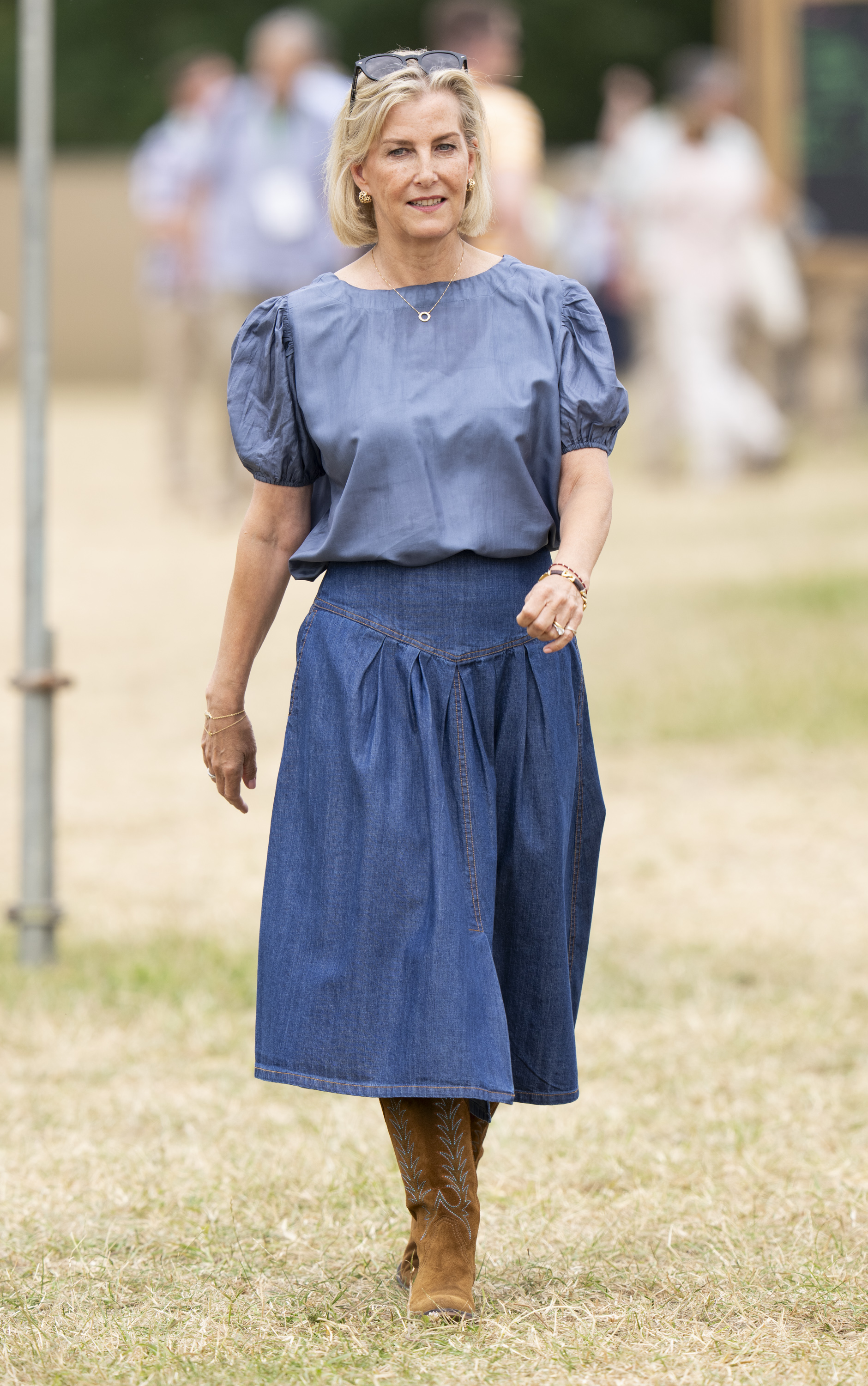 Duchess Sophie wearing a denim skirt and cowboy boots walking in a field