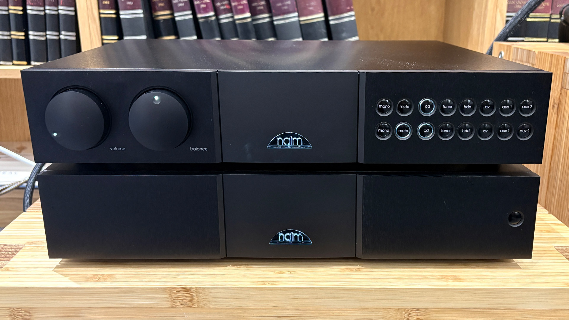 Naim NAC 552 pre amplifier on wooden hi-fi rack in front of bookcase