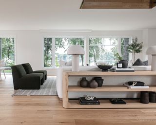 modern living room with wood floors and gray rug and long wooden console table behind sofa