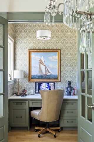 closet home office with damask style wallpaper, sage green desk and glass doors, leather chair, artwork