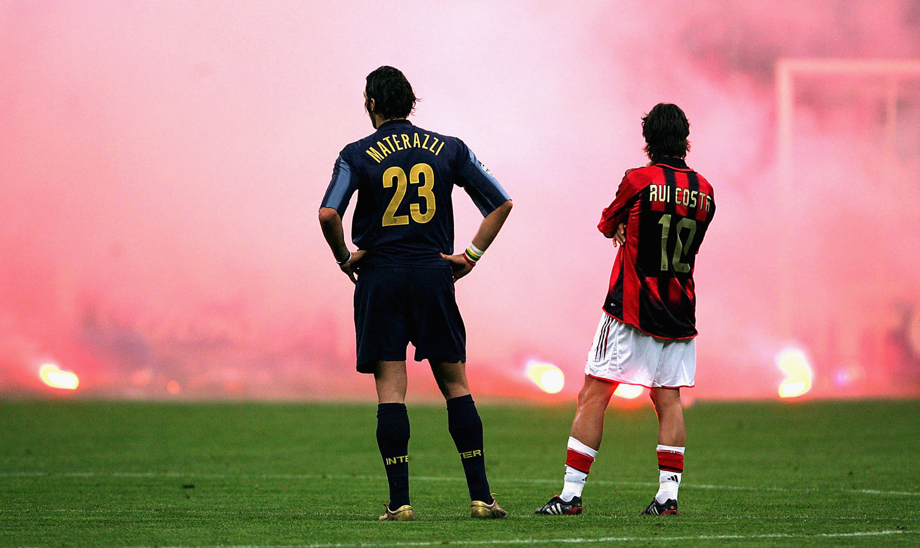 Marco Materazzi of Inter and Rui Costa of Milan look on as the pitch is showered with flares during the 2004/05 Champions League quarter-final second leg match at San Siro