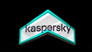 The Kaspersky logo on a stand at Mobile World Congress 2023, shot from below. It is grey text against a green border, set on a dark background,