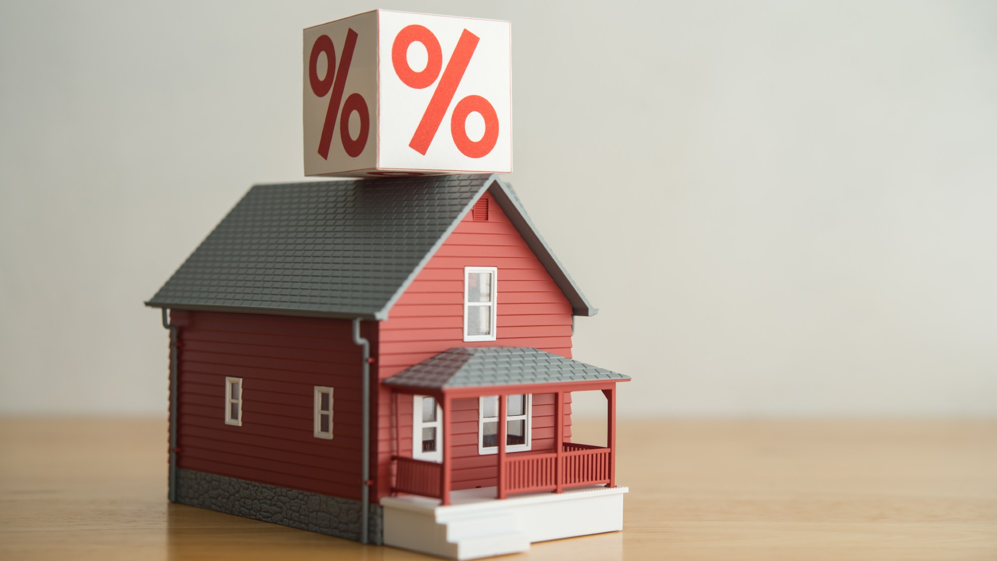 Red miniature house model with a block that has a percentage sign sitting on top of it