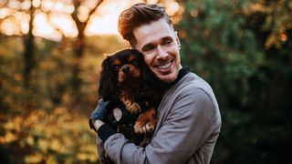 Man cuddling Cavalier King Charles Spaniel