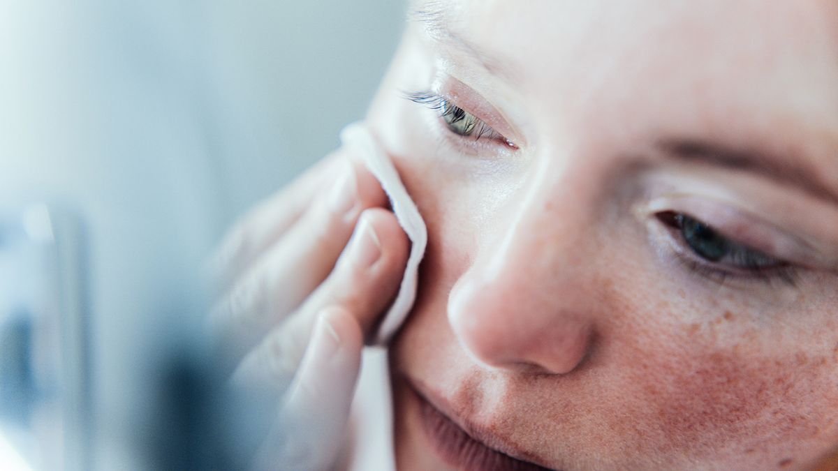 close up of a woman cleaning her face with a cotton pad