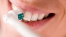 How to use an electric toothbrush: Image shows woman cleaning teeth