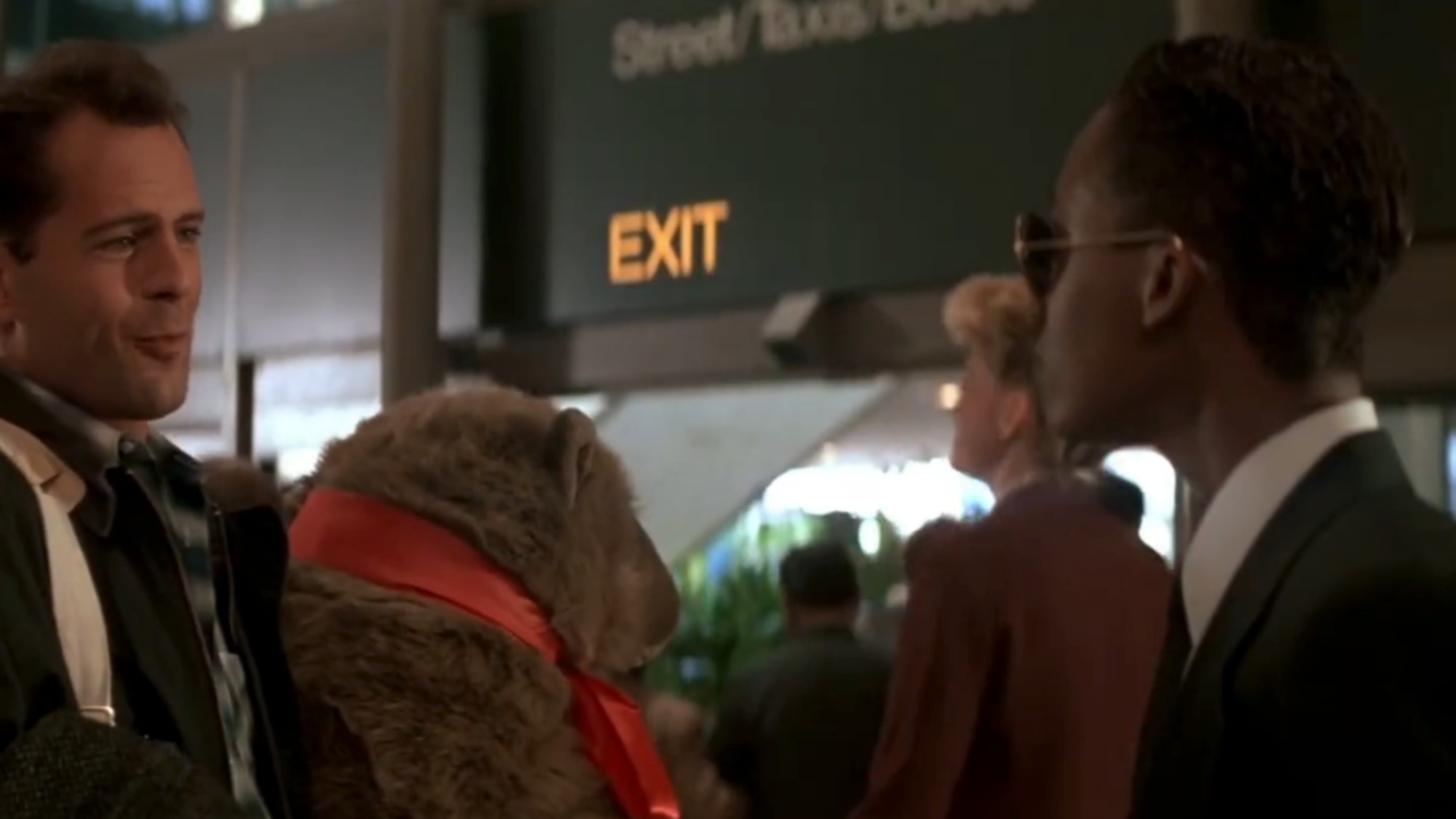 Bruce Willis on the left, holding a teddy bear with a red bow in Die Hard