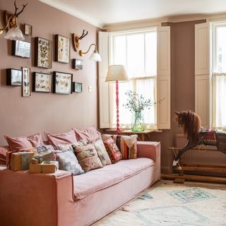 pink living room with large pink sofa, rocking horse and butterfly taxidermy wall art