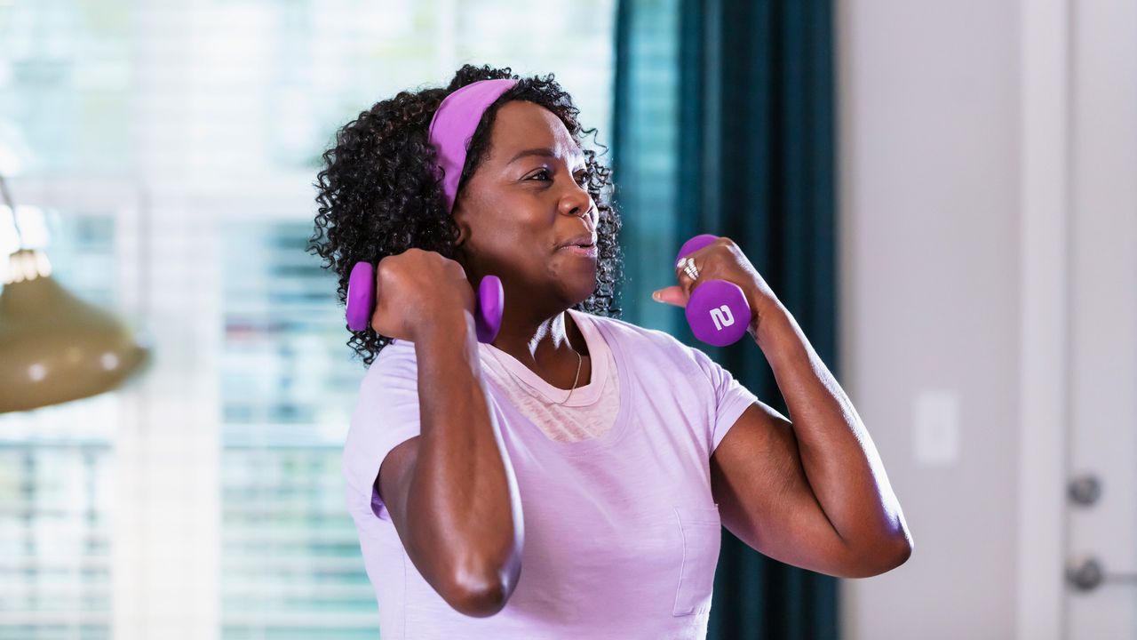 Woman performs biceps curls with a pair of 2kg dumbbells